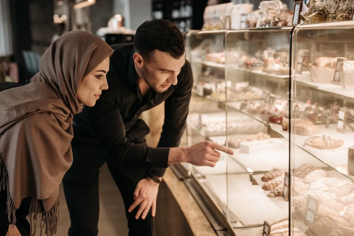 Twee klanten kiezen gebak bij de vitrine van een bakkerij