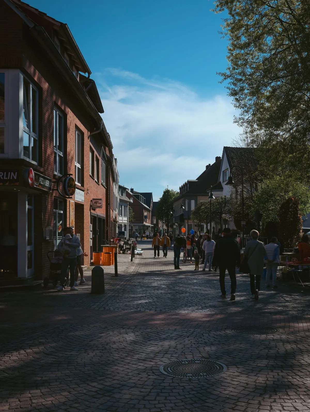 Winkelend publiek slentert door een zonnige winkelstraat met lokale winkels